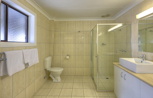Large bathroom with glass framed shower, vanity and toilet.