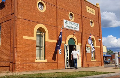 Man entering red brick historic Federation Museum building with flags out front